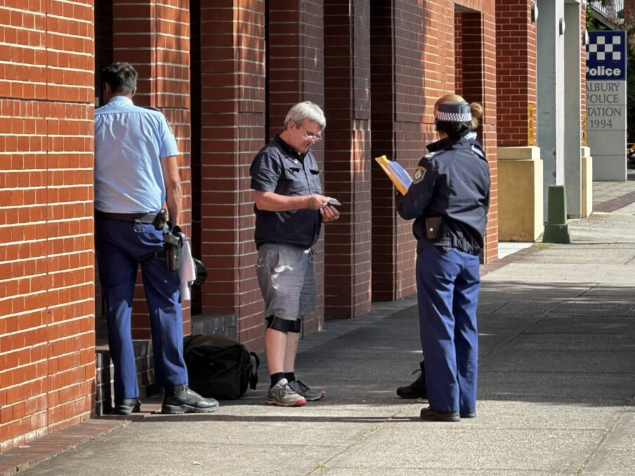Police speak to a man outside Albury's courthouse on Tuesday morning after the building was evacuated over a duffel bag left abandoned outside. Picture by Nigel McNay