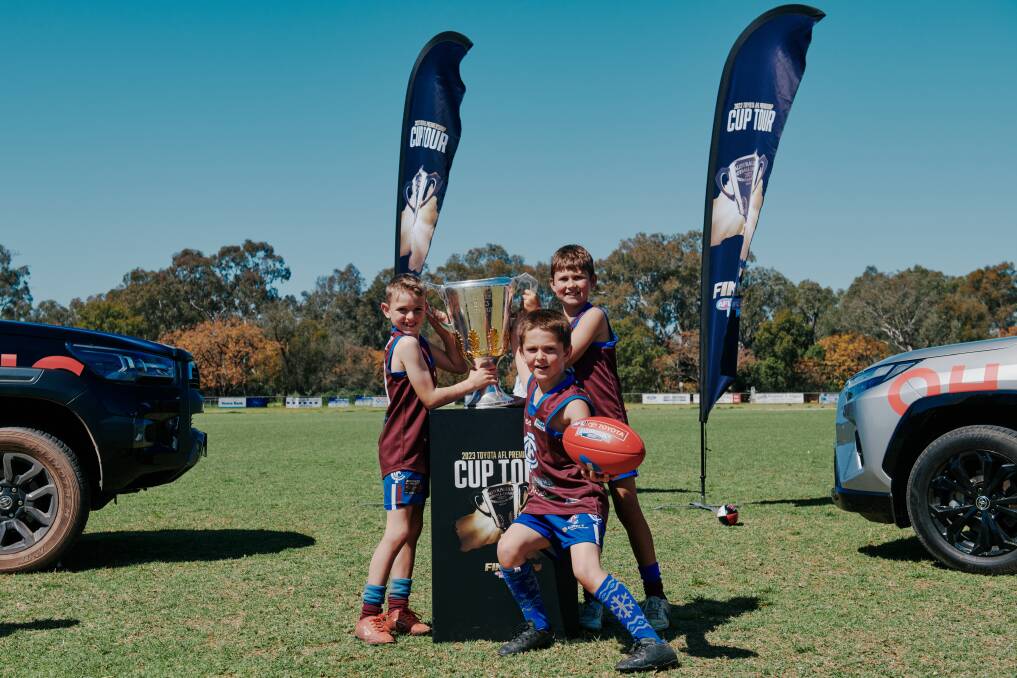 Ollie Sheather, Jacob Mair and Hudson Bootsma savour the touch of the cup as it stops at Culcairn Football Netball Club for the first time. Picture by Chris Gurney