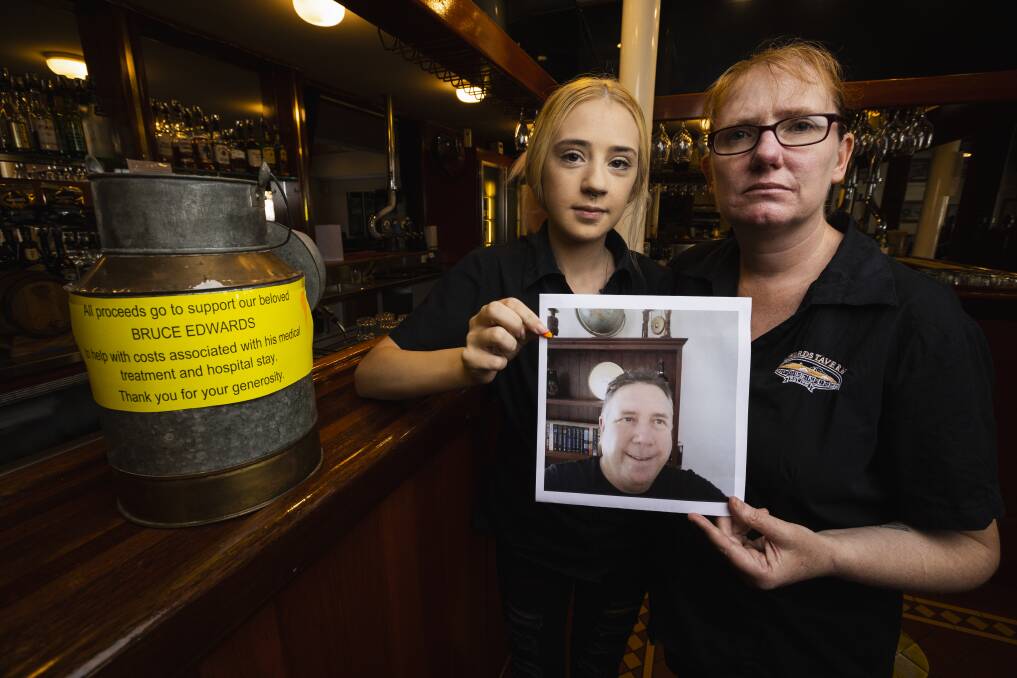 Eddie's workers Maddi Waite and Tracy Boon, with a picture of Mr Edwards taken at a staff meeting before he suffered a stroke last November. They say the pub "family" is devastated at the loveable larrikin's plight. Picture by Ash Smith 