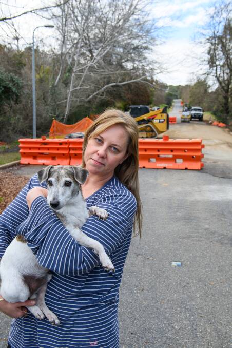 Resident Helen Zoudlik with her dog BJ say they are relieved the sinkhole on Bells Flat Road near Yackandandah has been repaired but are concerned that, without traffic calming measures, the road will still be dangerous with "hoons speeding through". Picture by Mark Jesser
