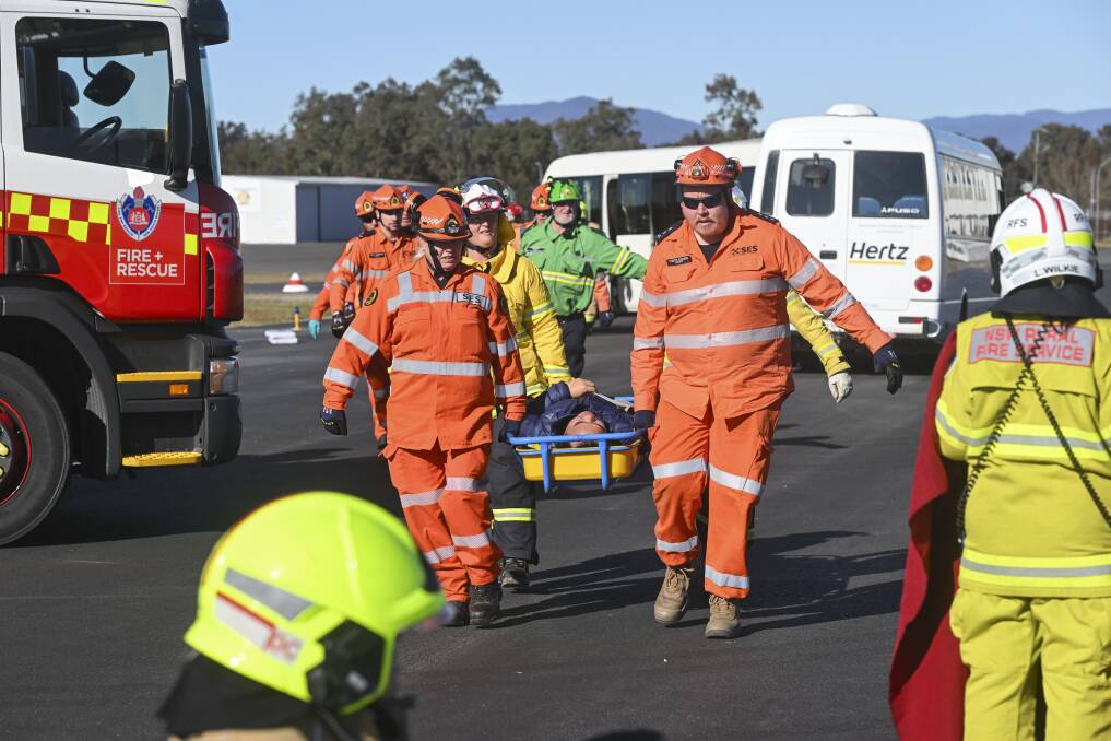 Emergency services carry an injured passenger in a stretcher to safety. Picture by Mark Jesser