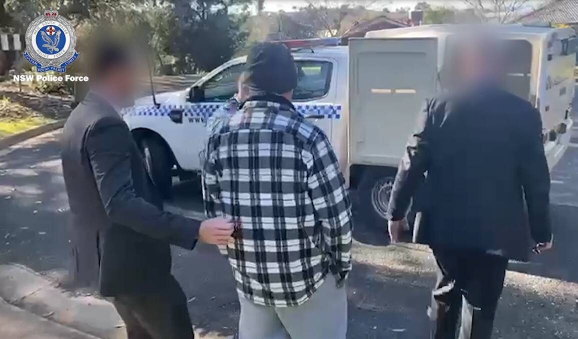 A man arrested in Wagga on Tuesday morning is escorted to the wagon by police. Picture by NSW Police