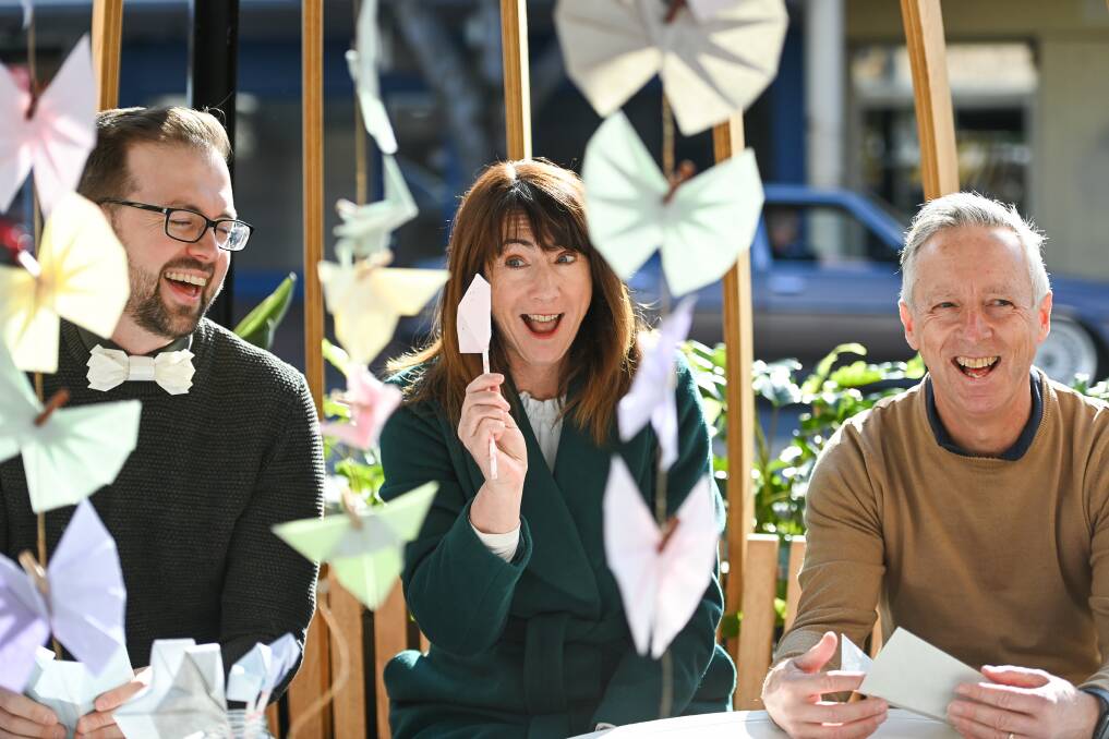 Paper giant: Albury mayor Kylie King celebrates completing her origami exercise as paper artist Cameron Walls and Albury Business Connect chairman Barry Young share in the mirth. Council is organising activities at the pods to attract users. Picture: MARK JESSER 