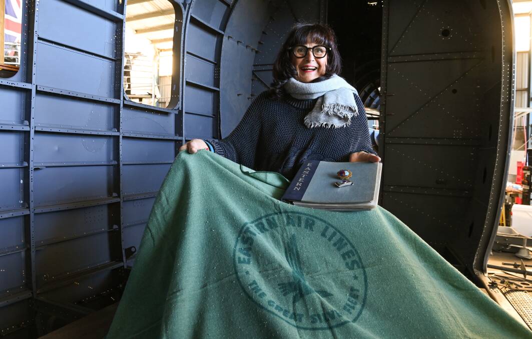 Claire Doolan sits with a folder, badge, buckle and Eastern Air Lines blanket in the fuselage of the DC-2 plane which once flew between New York and Miami. Picture by Mark Jesser