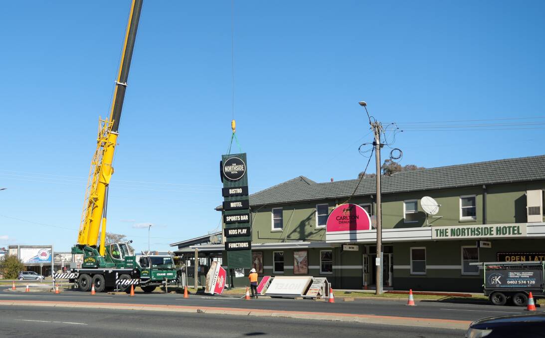 The new sign is lifted up by the Pickles crane from Urana Road while its predecessor lies nearby after being removed. Picture by James Wiltshire 