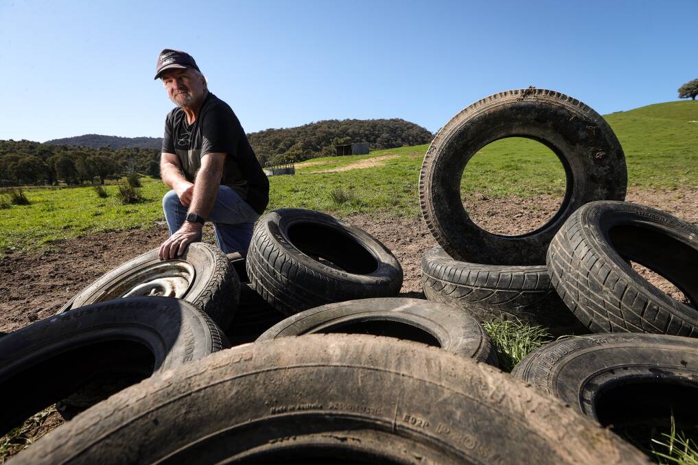 Alex Wolf with 10 tyres thrown from a vantage point overlooking his Indigo Valley property. They have been collected after landing over a wide area. Picture by James Wiltshire