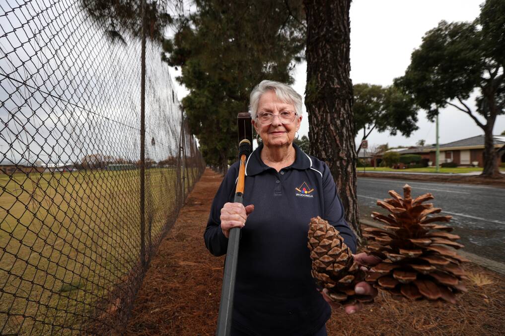 Croquet player Bev Zuber with her mallet and some of the cones which have fallen from pine trees which overlook her playing area at the Wodonga Tennis Centre. Picture by James Wiltshire