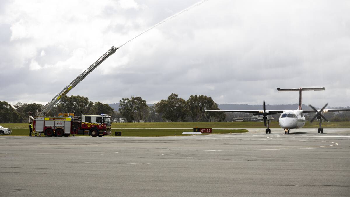 Ceremonial welcome: An Albury fire brigade truck sprays water over the Qantas turbo-prop as it taxies to the terminal after flying in from Adelaide. Picture: ASH SMITH