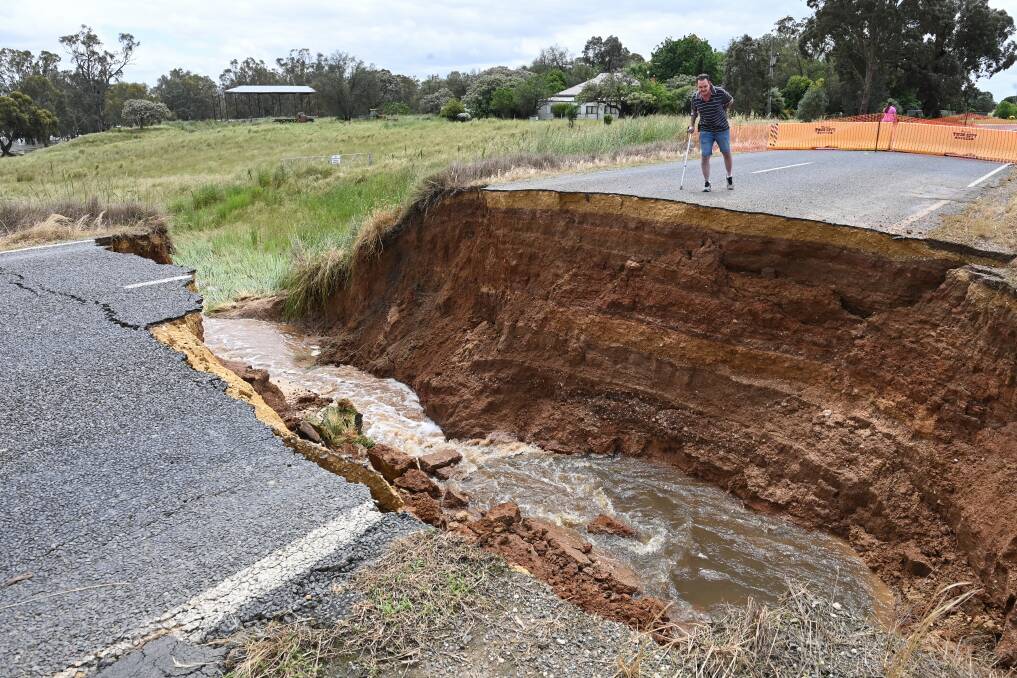 The gorge of Gooramadda Road. Neighbouring resident Anthony Morris glances over the crevasse created by excess moisture under the bitumen. Pictures by Mark Jesser