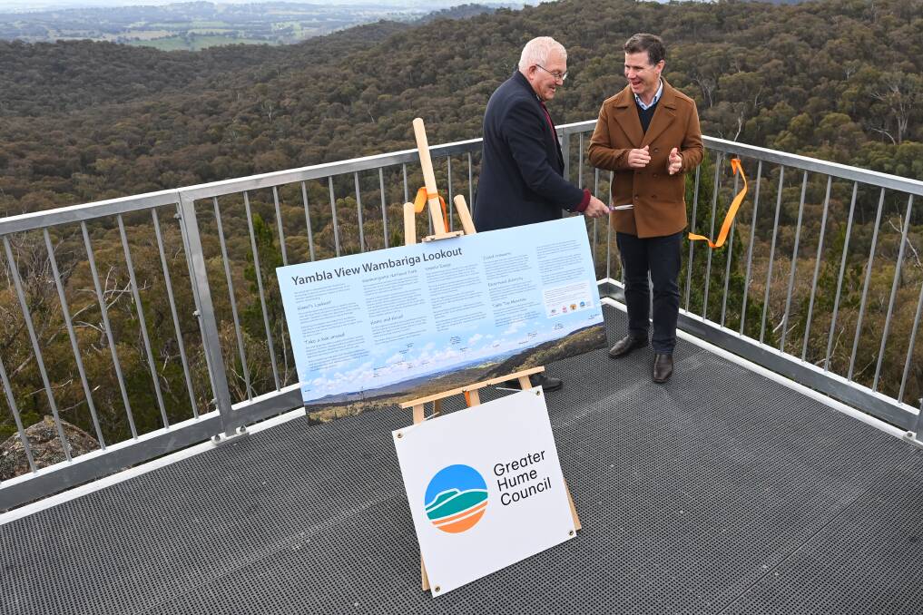 Greater Hume mayor Tony Quinn cuts the ribbon to open the vantage point as Albury MP Justin Clancy applauds. The sign about the lookout will replicated in metal form at the site and installed in September 2023. Picture by Mark Jesser