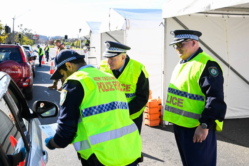 On the job: NSW police commissioner Mick Fuller (centre) and assistant commissioner Scott Whyte (right) observe as a motorist is stopped at Albury's Wodonga Place checkpoint on Thursday. Picture: MARK JESSER
