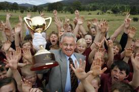 Then president of the Dederang Picnic Race Club Neville Seymour holds the Melbourne Cup among primary school students when it visited the course in 2009. Mr Seymour spent 58 years on the committee and had a stand named for him this year. 