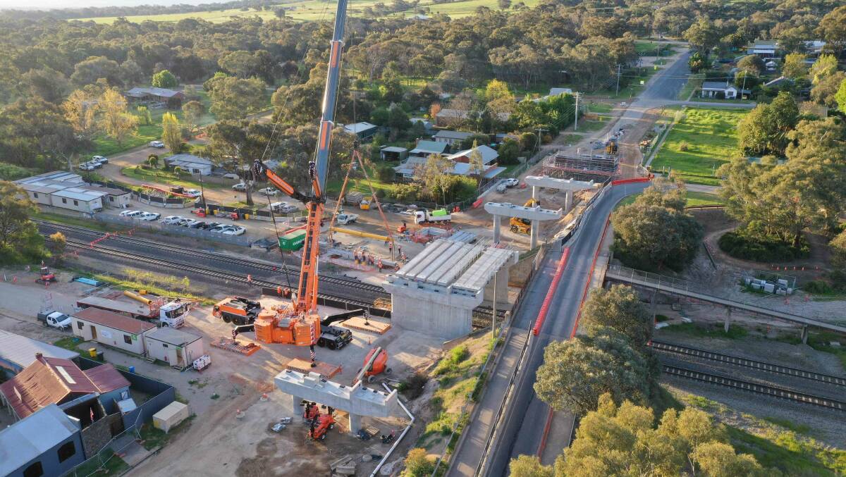 Beams are lowered into place to help form the deck of the new bridge across the railway line at Glenrowan. Picture supplied by the ARTC.