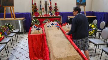 An attendee at last year's field of remembrance service with the three plots of sand into which little crosses are placed at St Matthew's Church in Albury.
