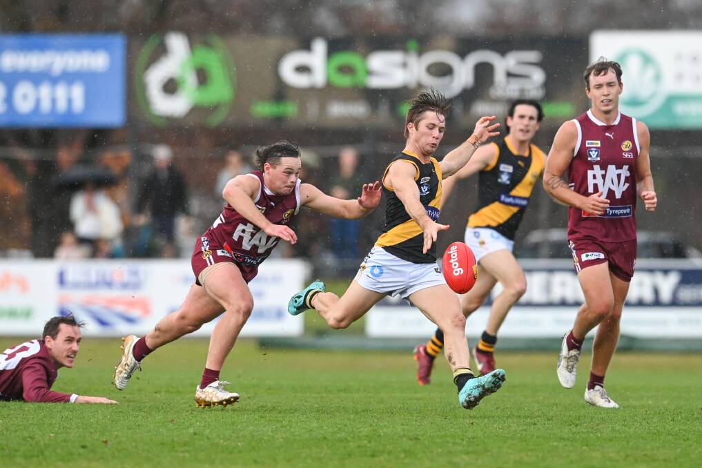 Albury's Jake Gaynor gets his kick away, despite the best efforts of Wodonga's Josh Mathey on Saturday. Albury blitzed the Bulldogs early, cruising to a 44-point win. Picture by Mark Jesser