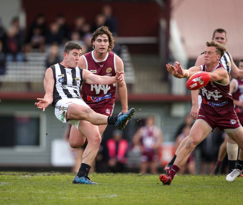 Wangaratta's Daniel Sharrock gets his kick away, despite the pressure from direct opponent, Wodonga's Angus Baker. Picture by James Wiltshire