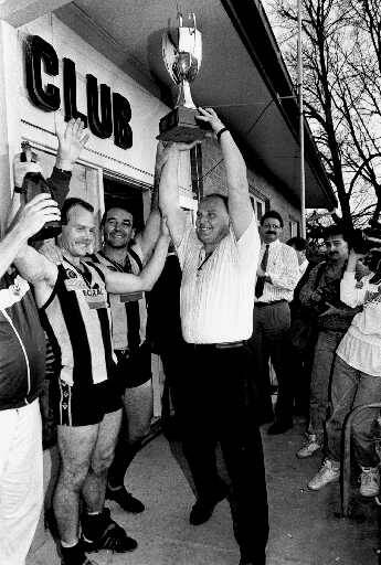 Wodonga coach Jeff Gieschen holds the 1990 premiership trophy aloft.