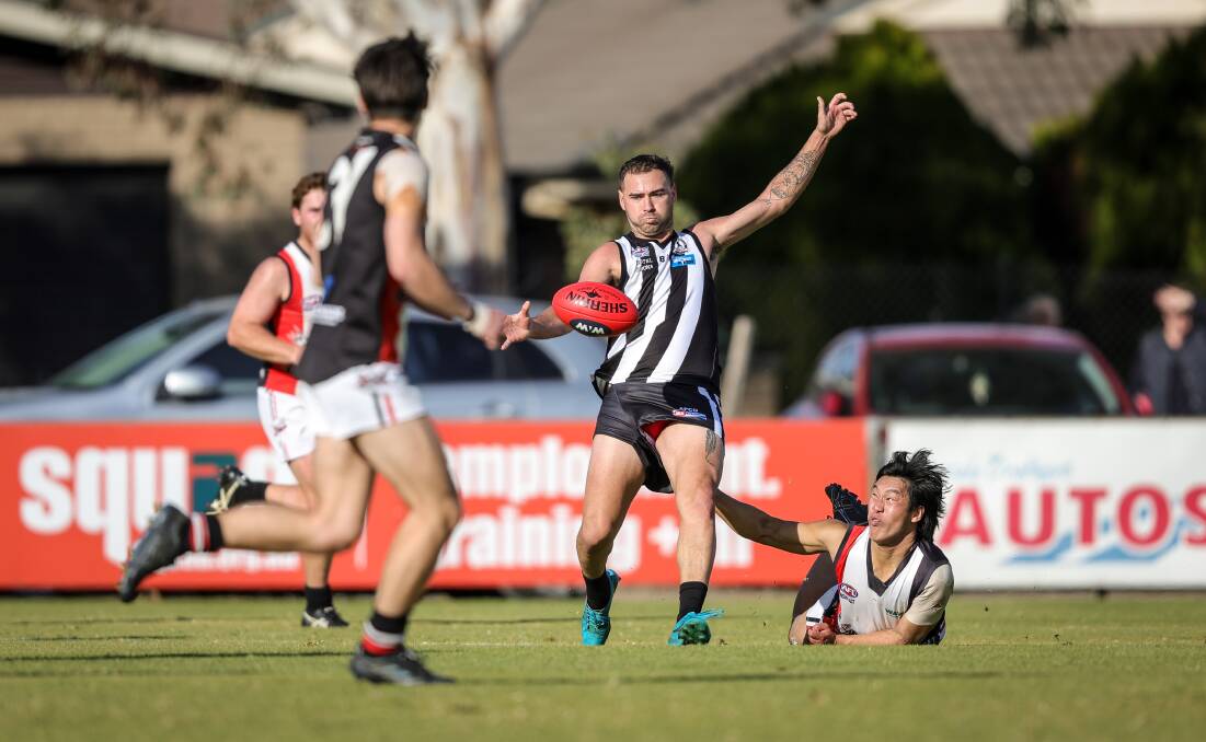 Magpies coach Dylan Dos Santos gets a kick away as Saint Nathan Tran applies some pressure. Picture by James Wiltshire