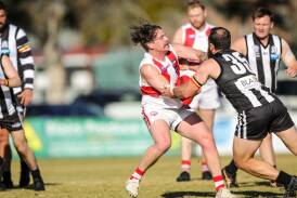 Henty's Daniel Smith tries to evade a tackle from Murray Magpies' Hayden Edwards at Urana Road Oval on Saturday. Picture by James Wiltshire