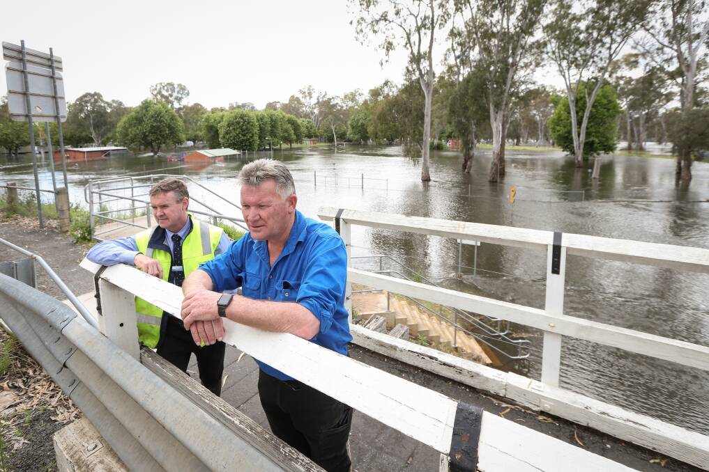 Federation Council general manager Adrian Butler and mayor Pat Bourke assessing the floodwater flowing around the John Foord Bridge between Corowa and Wahgunyah on Monday. Picture by James Wiltshire