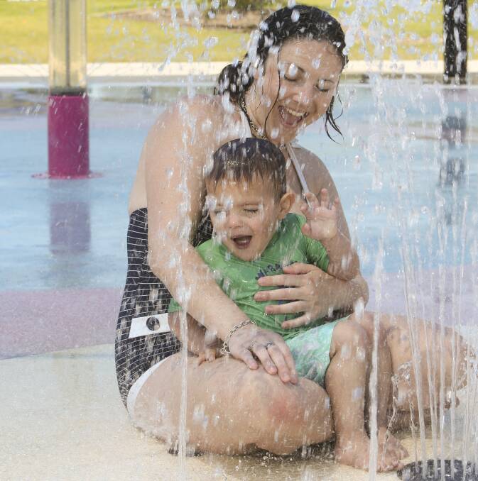 FUN IN THE SUN: Suzanne Walker, of Wodonga, and her son, Nixon, 2, survive the heat and take shelter under a water fountain at Waves, Wodonga, on Wednesday afternoon. Pictures: ELENOR TEDENBORG