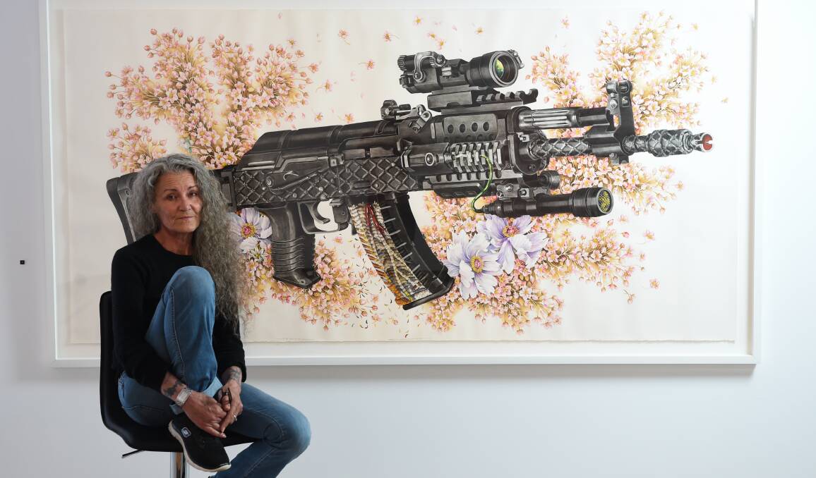 SOUR AND SWEET: Artist eX de Medici sits in front of her piece Eutelsat has turned you off (AK47) at her Sour Crude exhibition at MAMA. Picture: MARK JESSER
