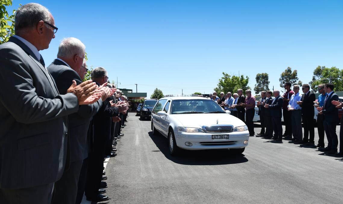 MARK OF RESPECT: Wodonga Bulldogs' past and present players applaud the hearse carrying the coffin of club favourite son Ken Goyne from the Lester & Son funeral home. Picture: MARK JESSER