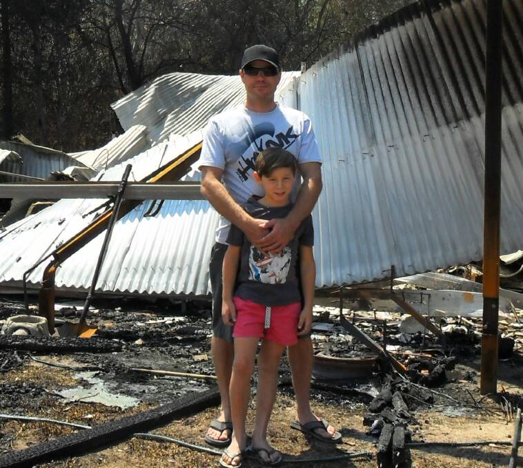 DISASTER ZONE: Aaron Tait and his son Damian, 8, visit their fire-damaged home. Pictures: Gay Miller