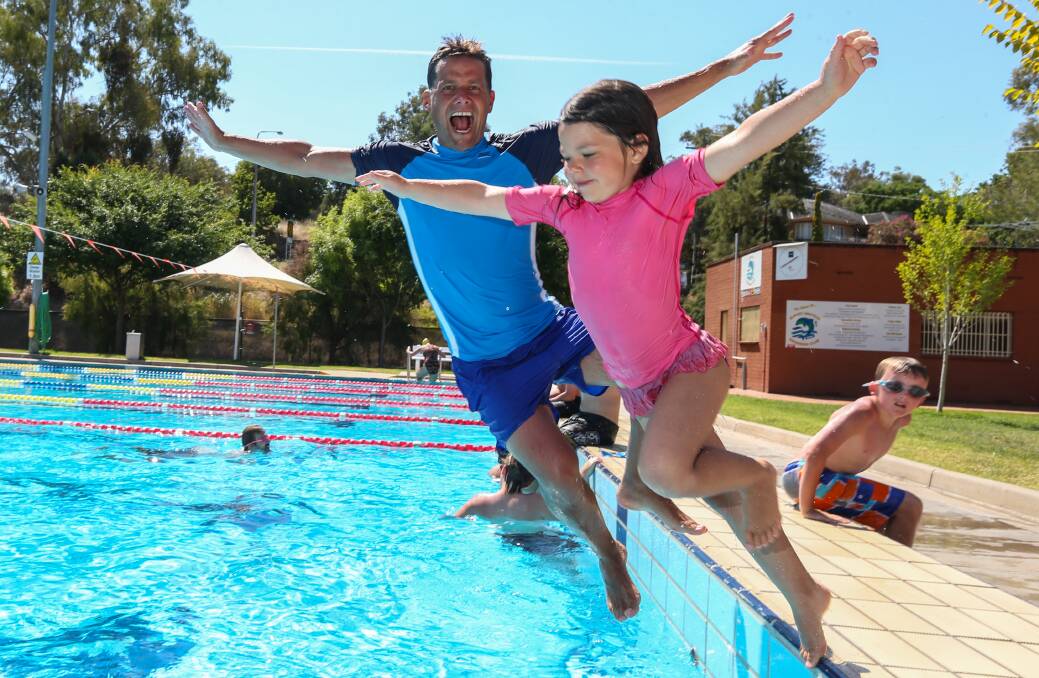 DEEP END: Chris Mitchell and his daughter Lucy Mitchell, 5, from Tallangatta jump off the blocks to cool off at the Albury Swim Centre on Friday.