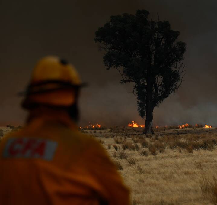 DARK DAY: A Baranduda CFA firefighter looks out at the flames on Monday which slowly crept toward the buildings at the Middle Indigo Primary School. Pictures: MARK JESSER