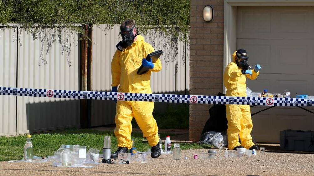 Police wearing protective equipment remove various containers containing clear liquids from a house on Nelson Drive in North Grove. Picture: Anthony Stipo.