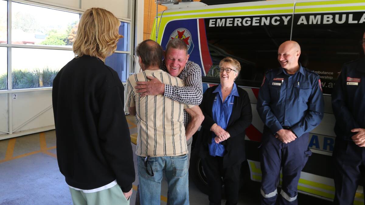 Doug Butler and truck driver Kevin Williams hug in Wodonga on Wednesday, surrounded by those who helped save Mr Butler's life. Mr Butler stopped breathing for nearly half-an-hour after a heart attack. Picture by Blair Thomson