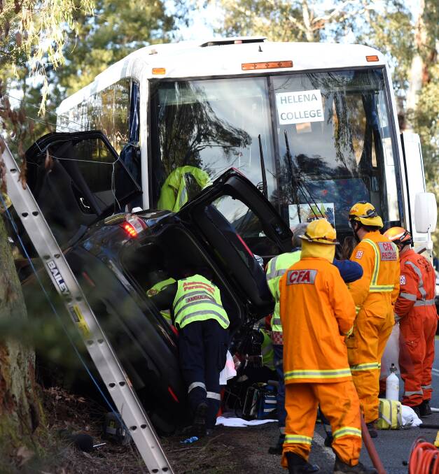 CRASH: Emergency crews work to free a woman from her car after it hit a bus at Dederang on Friday. Picture: MARK JESSER