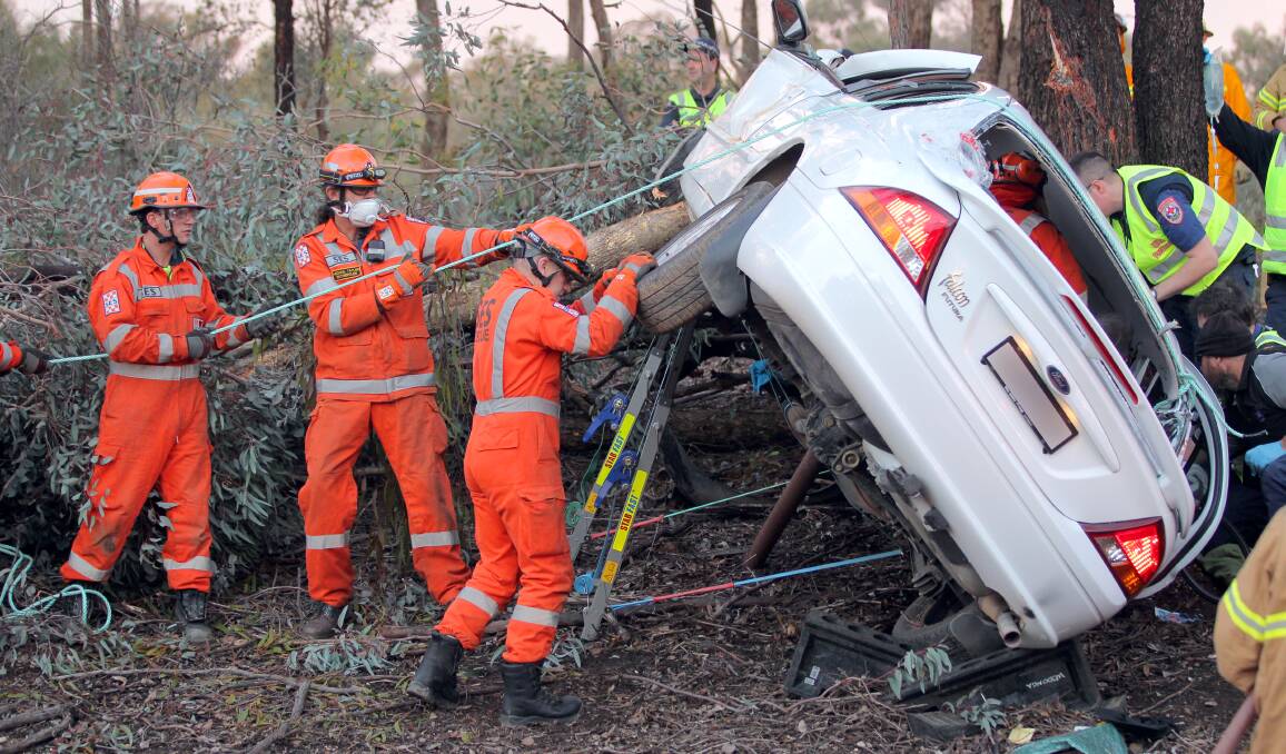 HELP: SES volunteers stop a car from tipping over on the side of the Hume Highway on Thursday as paramedics treat the driver. Picture: BLAIR THOMSON