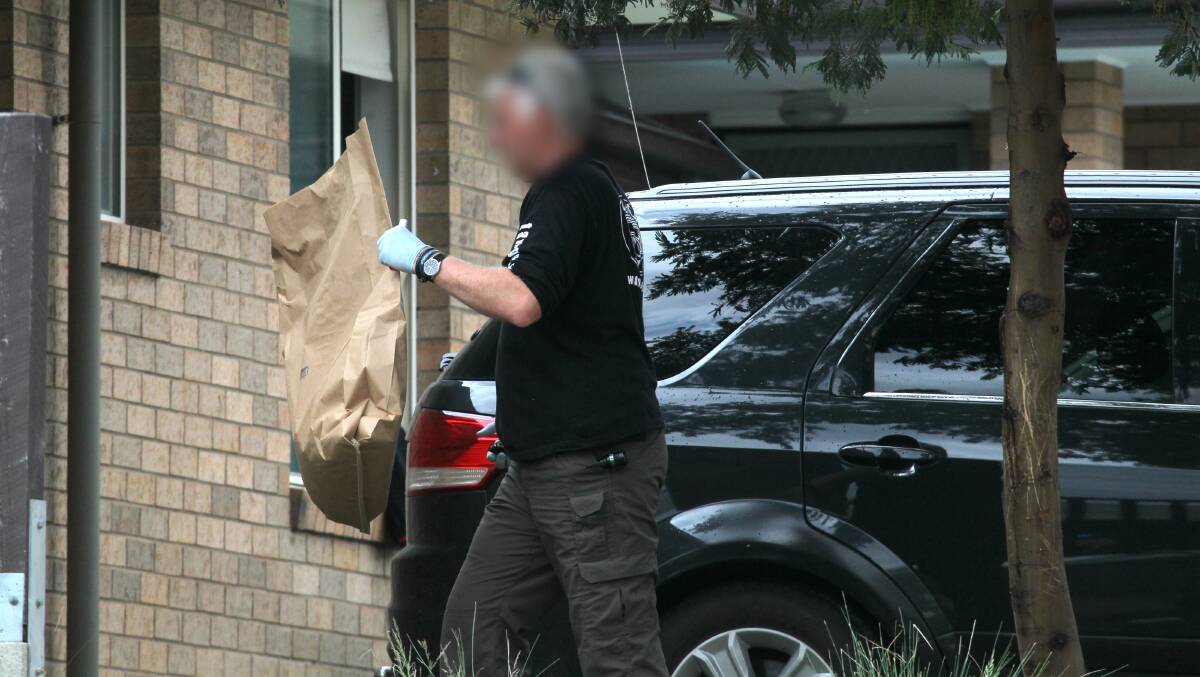 WARRANT: An officer removes evidence from the Stott Court home on Thursday morning. Picture: BLAIR THOMSON