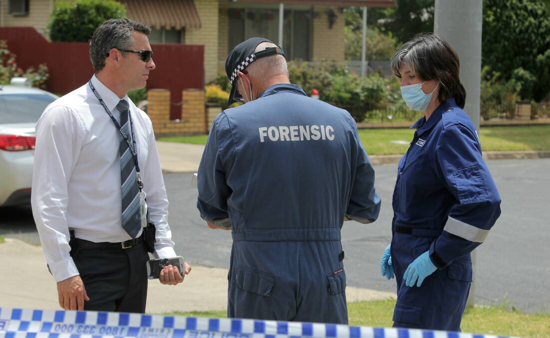 CRIME SCENE: Detective Sergeant Graeme Simpfendorfer speaks to forensic officers outside the home. Picture: BLAIR THOMSON