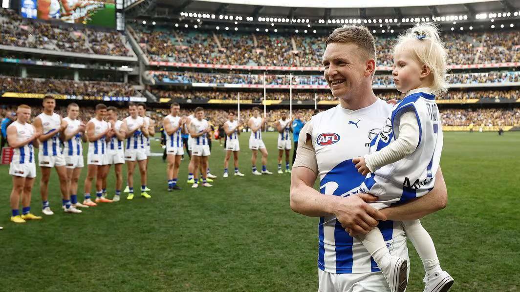 Jack Ziebell, holding daughter Pippa, leaves the MCG to a standing ovation after his final match for North Melbourne. Picture from AFL Photos