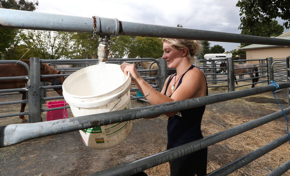 Refuge: Jess Bamaszczyk gets water for one of the horses at Wodonga racecourse, which was opened for people trying to protect lifestock. Picture: JAMES WILTSHIRE