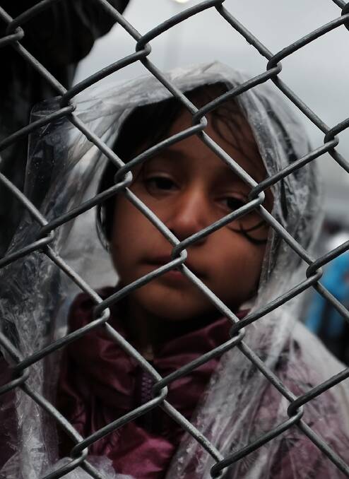 PLEASE HELP: A child waits at a migrant processing centre in Greece.